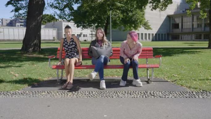 一群年轻人坐在公园的长凳上，两人离开