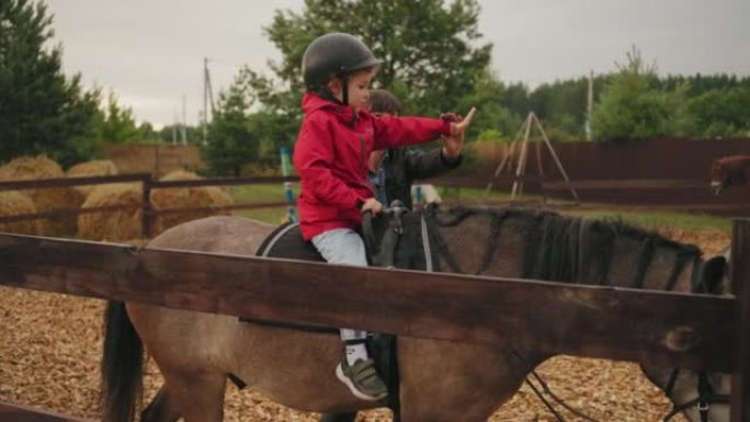 蹒跚学步的孩子正在马术中心学习骑马，小马俱乐部的儿童海马疗法