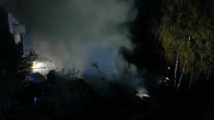 一群消防员夜间灭火的无人机飞行视点。危险烟雾危机