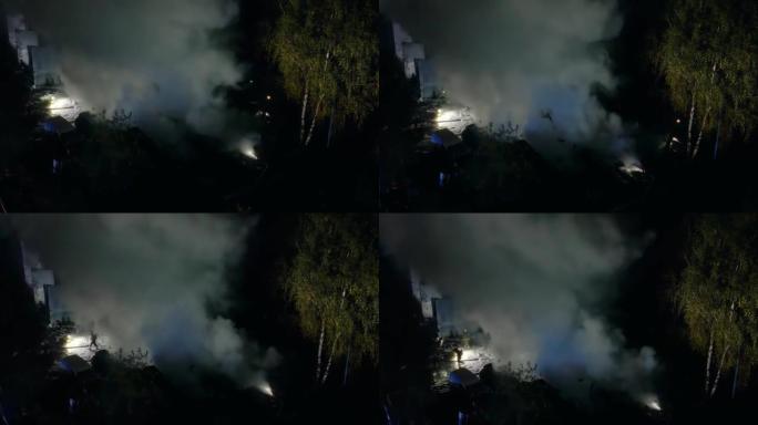 一群消防员夜间灭火的无人机飞行视点。危险烟雾危机