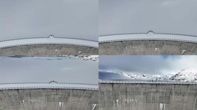 空中无人机拍摄了一名男子站在山上积雪覆盖的大坝上