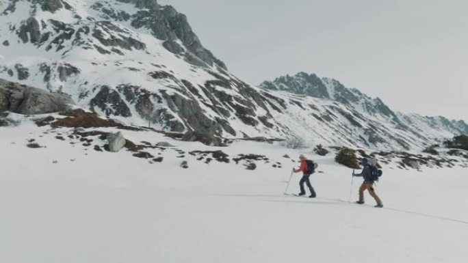 两名滑雪者在雪山上徒步旅行的空中无人机拍摄