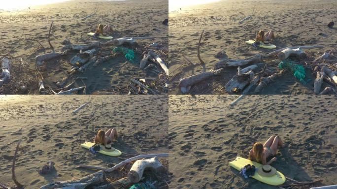 日出时在海滩上放松的年轻女子的鸟瞰图
