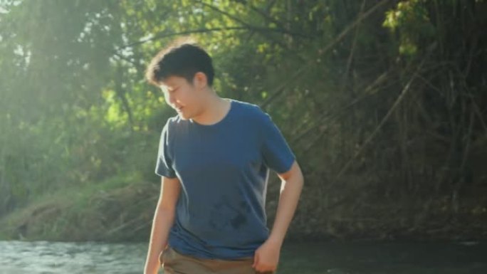 快乐的亚洲男孩在丛林中的河里放松阳光，户外生活方式的概念。