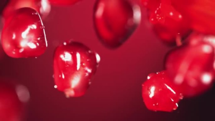 红色背景下新鲜石榴籽与水边碰撞的超慢动作镜头