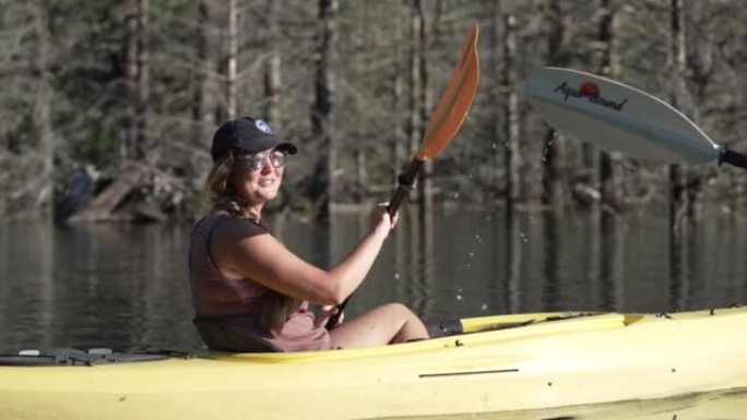 一名女性皮划艇运动员在河里微笑和划桨的细节照片