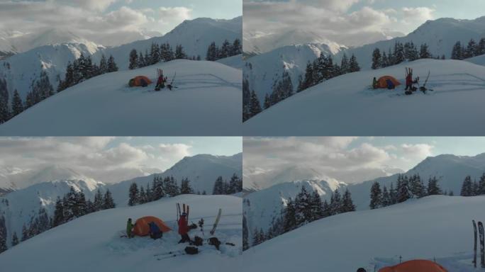 一群滑雪者在雪山上的帐篷周围的空中无人机拍摄