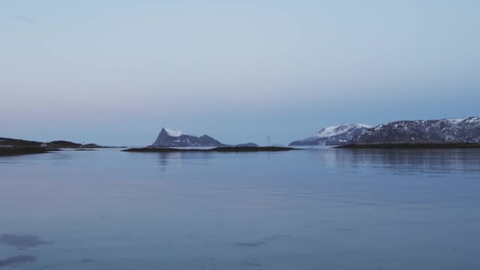 冬天特罗姆瑟海边的风景。积雪覆盖的山脉和杂草