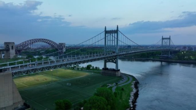美丽的特里伯勒桥，下面有足球场。背景下的地狱之门桥。纽约的桥梁在晚上。