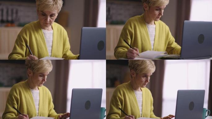老太太正在网上学习或工作，在笔记本电脑上上网，在笔记本电脑上做笔记，在家中的退休妇女肖像
