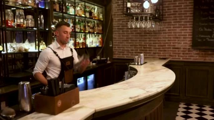 英俊的男调酒师在酒吧柜台用摇床制作鸡尾酒