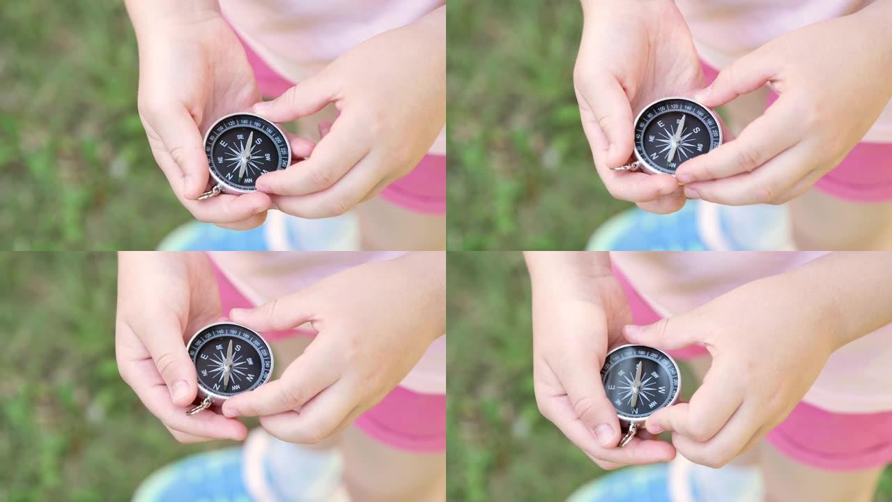 学龄儿童，女孩手里拿着一个简单的指南针，寻找北方，户外拍摄，物体细节，特写。找到正确的道路、正确的方