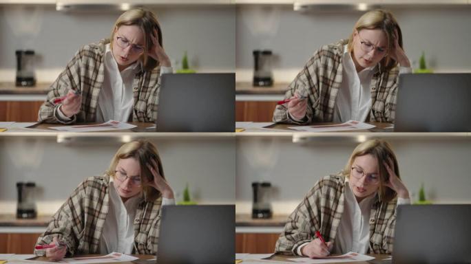 该名女子坐在一张桌子旁，坐在笔记本电脑旁，用毡尖笔在图表上标记数据。紧张地在视频链接上交谈