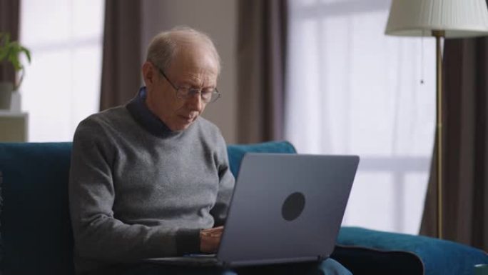 老人周末在公寓里用笔记本电脑上网，退休人员在键盘上打字，在社交网络中交流或远程工作