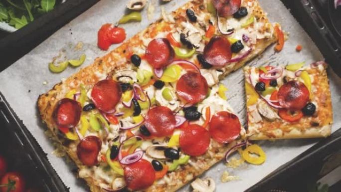 一块方形比萨饼，罗勒意大利辣香肠西红柿和蘑菇放在铁托盘上