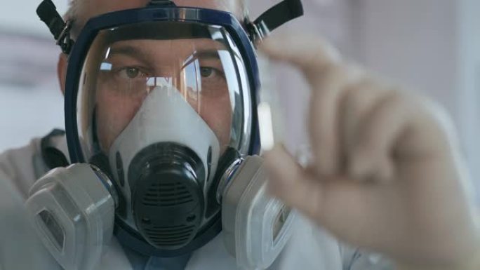 一家制药公司的科学家医生在实验室的玻璃呼吸器屏幕上开发一种药物，手里拿着一种新药。白色护身符，带有针