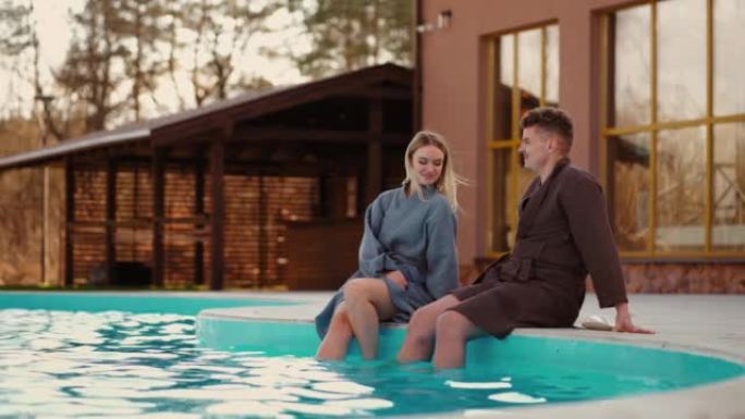 恋人在温泉浴场休息，在室外游泳池的温水中展示双腿