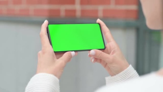 Outdoor Woman Looking at Smartphone with Green Chr