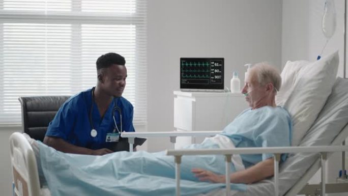 一位黑人心脏病专家医生正在与一名60-70岁的患者躺在医院的床上交谈。神经科医生正在和病人谈话。患者