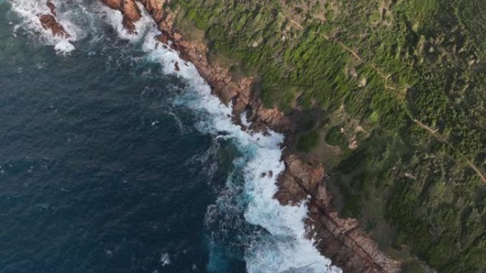 湛蓝海水的鸟瞰图，海浪冲入绿色的草地海岸线