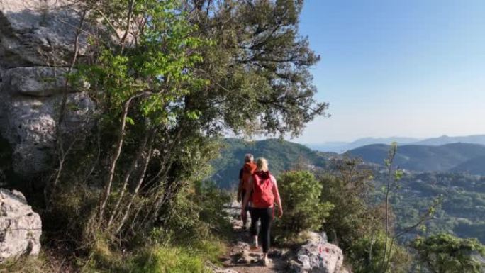 徒步旅行的夫妇沿着绿色山丘的山顶到达