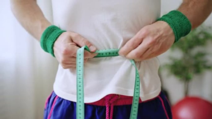 男人用胶带测量腰部，试图看起来更瘦，失重痴迷