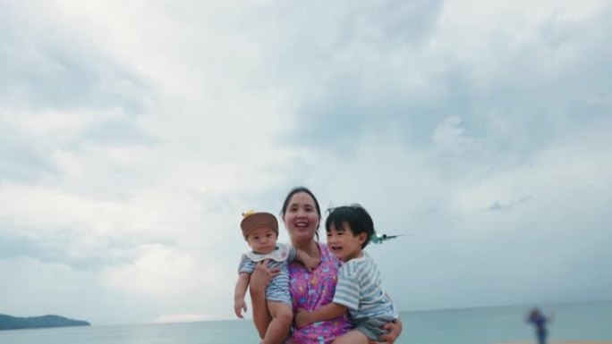 亚洲母亲抱着两个儿子从降落的飞机上奔跑