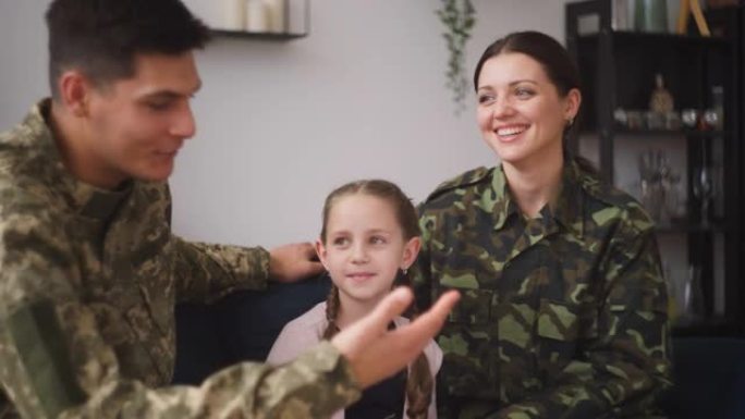 兴高采烈的军人爸爸妈妈抱着小女儿坐在沙发上，一家人