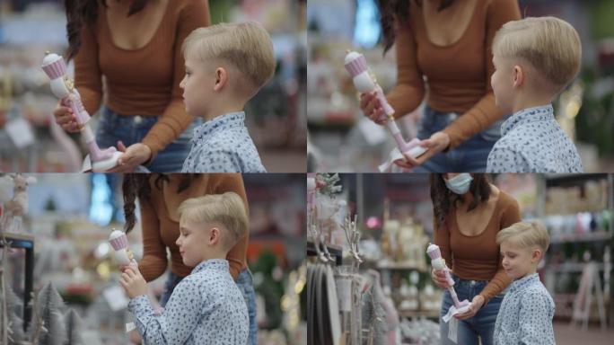 在大流行购物，戴着口罩的女人和儿子在儿童商店选择玩具，年轻的母亲在超市购买商品，预防病毒性疾病