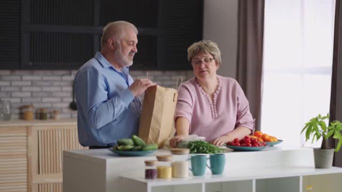 老年妇女正在打开装有食物的袋子，她的丈夫在市场上买了绿色植物和面包，老配偶