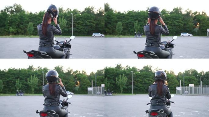 穿着骑自行车的皮衣的未知迷人年轻时尚苗条的女人坐在豪华摩托车上，戴上防护头盔