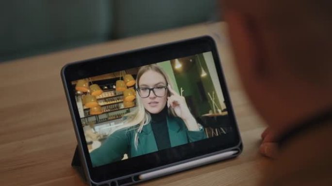 漂亮的金发女人从智能手机显示屏上向男友打招呼，通过互联网进行视频通话
