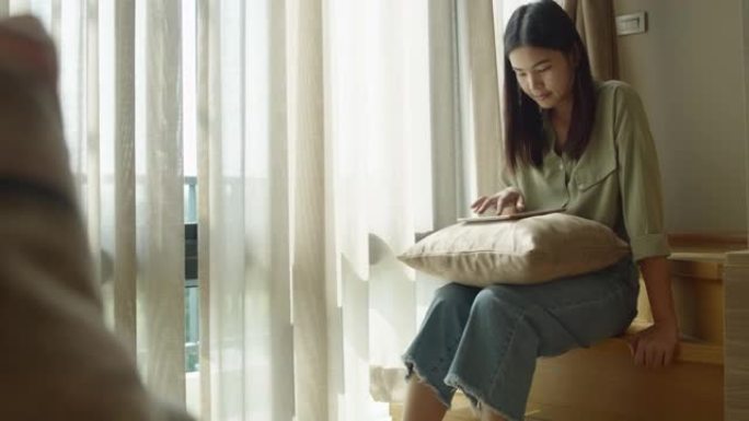 在家中的生活方式亚洲女孩呆在家里度假，在沙发上玩taplet。