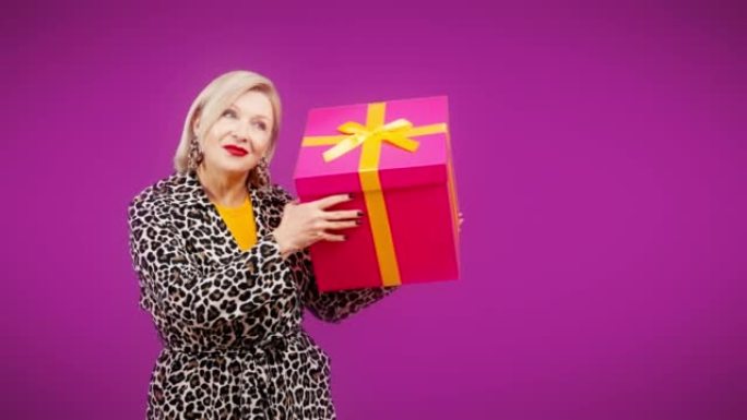 开朗的高级女人拿着巨大的礼品盒，圣诞节促销，生日礼物