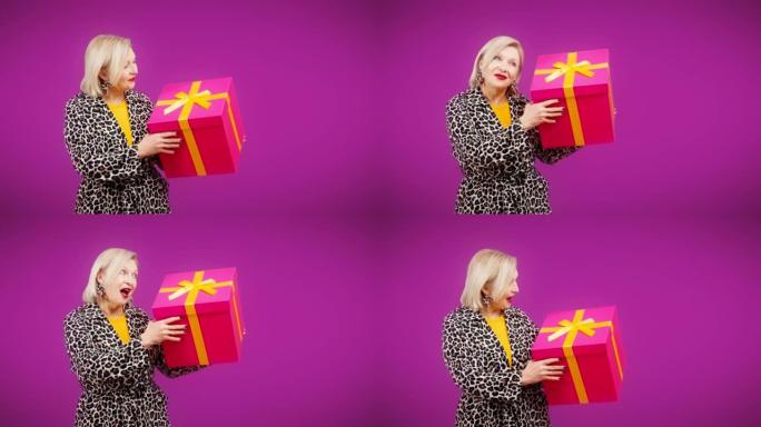 开朗的高级女人拿着巨大的礼品盒，圣诞节促销，生日礼物