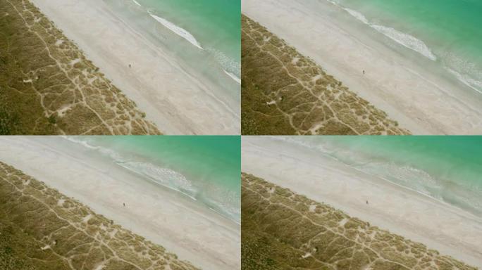 空中无人机拍摄阴天一个人在绿水青山的沙滩上行走
