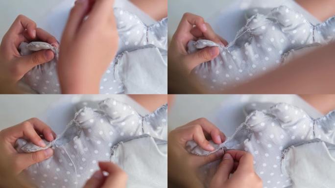 孩子的手缝制毛绒玩具的特写镜头。女孩缝了一个大象的毛绒玩具。手工制作，爱好。