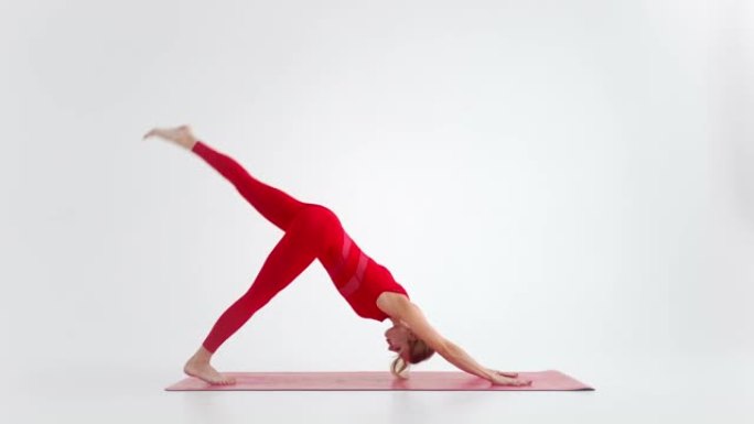千禧一代女性在瑜伽中伸展姿势冥想，在红色运动服的白色背景下孤立。年轻的女瑜伽练习者为复制空间摆姿势的