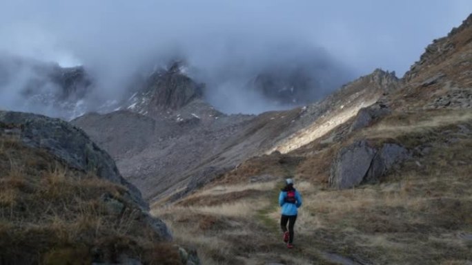 女子越野跑运动员在高山环境中跑步，雪峰在后面