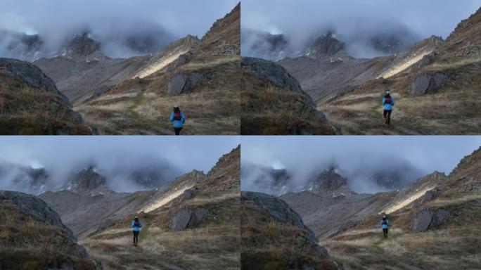 女子越野跑运动员在高山环境中跑步，雪峰在后面