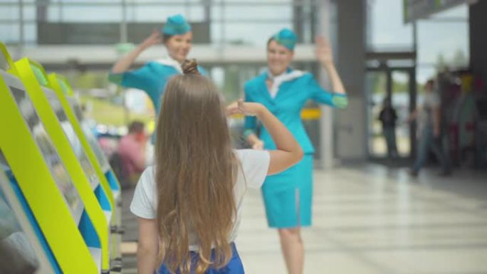 小女孩在机场向美丽的空姐致敬的背景图。机架焦点改变了微笑的白人女性，穿着空姐制服向黑发孩子致敬。等待