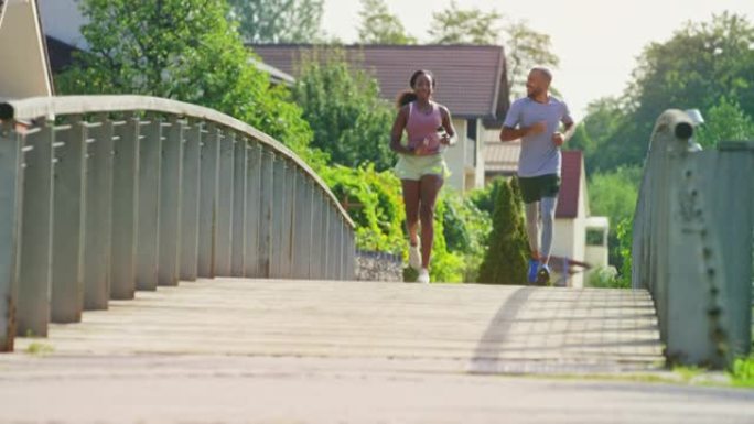 一个年轻的男人和女人在阳光下跑过桥