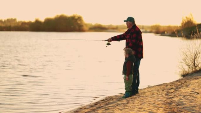 快乐的老人和孙子在河边休息，日落时分从美丽的海岸钓鱼，积极的休闲和生活方式