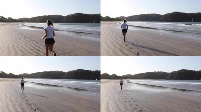 年轻女子沿着空旷的海滩奔跑，日出