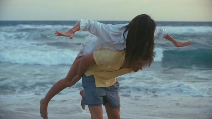 海滩上的浪漫情侣。爱的男朋友抬着女朋友到处玩