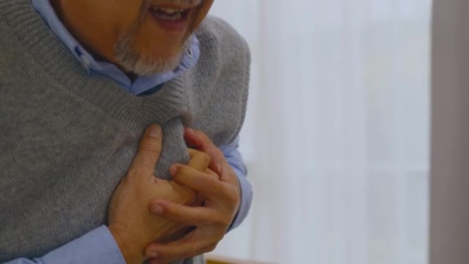 亚洲老人因心脏病而胸痛在客厅的沙发上。