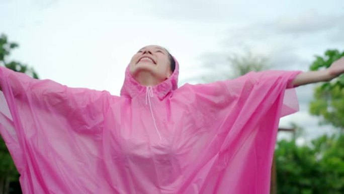 穿着粉红色雨衣的年轻美丽幸福的女人享受着rian的慢动作。