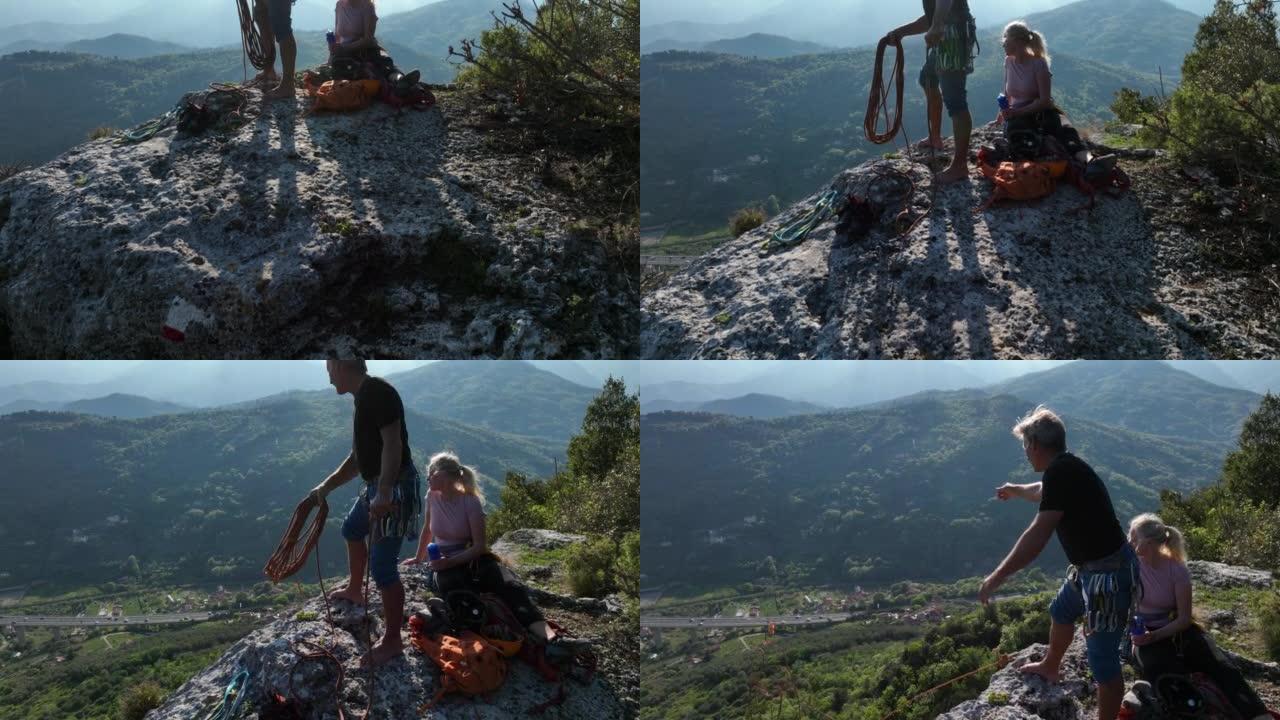 攀岩夫妇到达绿色山丘上方的岩石山顶