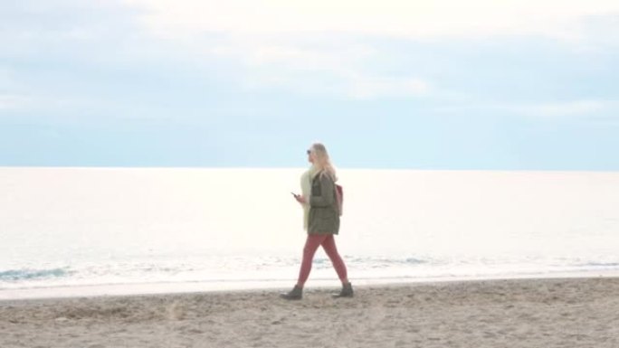 阴天，成熟的女人沿着平静的海边的海滩散步