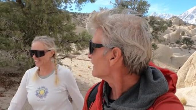 徒步旅行的夫妇沿着沙漠路线穿过岩石和灌木